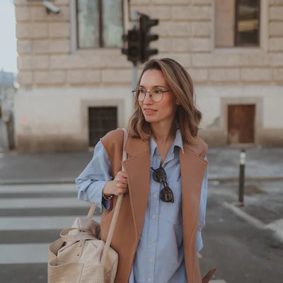 Žena s naočalama stoji na ulici i smiješi se